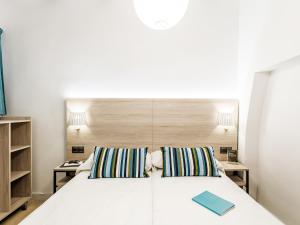 バレンシアにあるUNIK. Apartments Valenciaのベッドルーム1室(白いベッド1台、ナイトスタンド2台付)