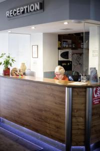 a woman sitting at a counter in an office at Hotel Slavie in Cheb