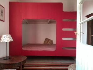 a red bunk bed in a room with a table at Kőpajta Vendégház in Barnag