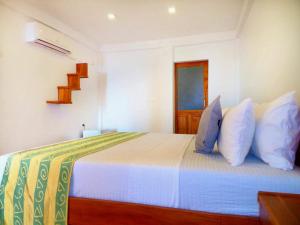 una camera da letto con letto, lenzuola e cuscini bianchi di Amour Surf a Tangalle