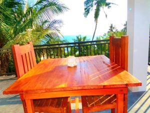 a wooden table and chairs on a balcony with palm trees at Amour Surf in Tangalle
