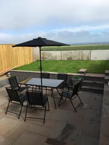 a table and chairs with an umbrella on a patio at Waters Edge in Penclawdd
