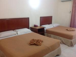 two beds in a hotel room with towels on them at Tanjung Demong Beach Resort in Kuala Besut