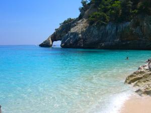 a beach with people swimming in the water at Cala Gonone Cozy House Sea View in Cala Gonone