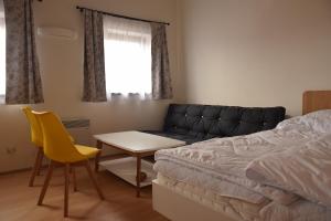 a bedroom with a bed and a table and a yellow chair at Apartmán Hejč in Moravská Nová Ves