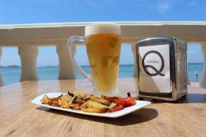 um prato de comida e uma caneca de cerveja em Apartamentos Dominique em La Manga del Mar Menor