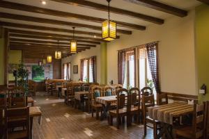 a restaurant with wooden tables and chairs and windows at Hotel & Restaurant Complex HAP-OK in Brodki