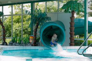 a man riding a water slide in a pool at Camping Ginsterveld in Burgh Haamstede