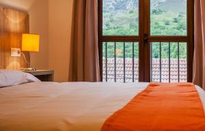 a bedroom with a bed and a large window at Apartamentos El Caxigu in Arenas de Cabrales