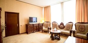 um quarto com cadeiras, uma televisão e uma mesa em Hotel Imperial Inn em Târgu-Mureş