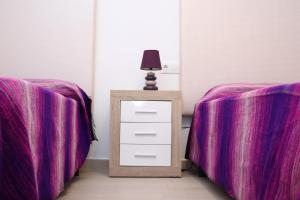 コニル・デ・ラ・フロンテーラにあるApartamento céntricoの紫色のシーツが備わるベッド2台、ナイトスタンド(ランプ付)