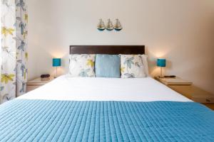 a bedroom with a large bed with a blue blanket at 1 Suffolk Cottage in Aldeburgh