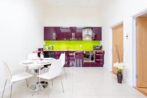a kitchen with purple and green cabinets and a table and chairs at 1 Suffolk Cottage in Aldeburgh