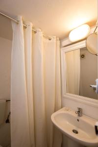 a bathroom with a white shower curtain and a sink at Hotel Delphines in Mikonos