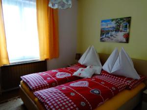 a bed with red and white blankets and pillows at Frühstückspension Irmer in Gaming