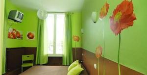 L'Hôtel L'Astrée في Feurs: غرفة خضراء مع سرير مع زهور على الحائط