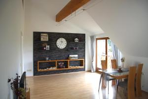 een woonkamer met een tafel en een klok aan een muur bij Ferien bei Maria in Alfter