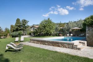 a swimming pool in a yard with two lawn chairs at Relais Villa Belpoggio - Residenza D'Epoca in Loro Ciuffenna