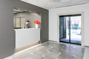 a man standing at a counter in a office lobby at Hotel Principe in Modena