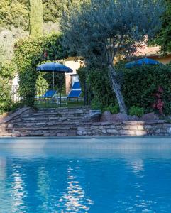 a swimming pool with a table and an umbrella next to the water at Tenuta La Bandita in Sassetta