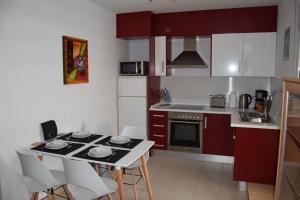 エル・ベルゲルにあるCasa Verdeのキッチン(赤いキャビネット、テーブル、椅子付)