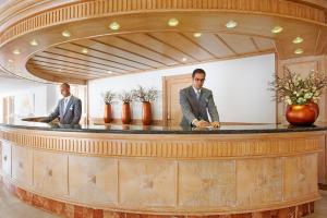 two men in suits standing at a counter at Grupotel Los Príncipes & Spa in Playa de Muro