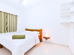 a white bedroom with two beds and a window at Residencial JL Maresias in Maresias