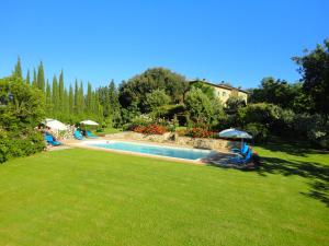 a swimming pool in a yard with chairs and umbrellas at Podere San Luigi in San Gimignano