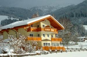 una casa con techo cubierto de nieve en la nieve en Apart-Pension Seiwald, en Wagrain