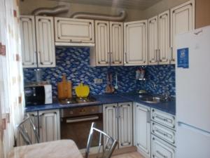カルーガにあるApartments on Plekhanova 53の白いキャビネットと青いタイルの壁が備わるキッチン