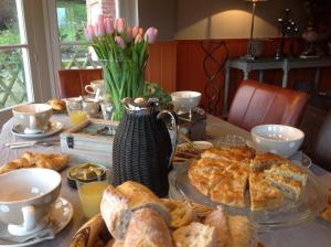 a table with bread and pastries and a vase of flowers at La Villa des Rosiers in Cricquebœuf