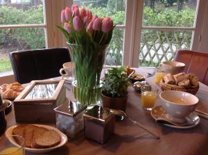 a table with a vase of pink tulips on it at La Villa des Rosiers in Cricquebœuf +36 photos