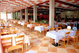 uma sala de jantar com mesas e cadeiras brancas em Hotel Aurora em Podgora