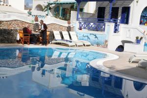 a man standing at a table next to a swimming pool at Samson΄s Village in Perissa