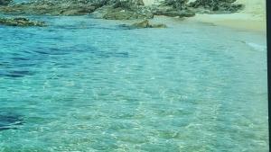a body of water with a beach and rocks at Casa De S'Arca in Torre Dei Corsari