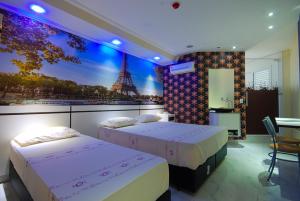 two beds in a room with a view of the eiffel tower at Motel Fest (Adults Only) in Santo André