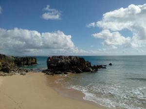 a beach with rocks and the ocean on a cloudy day at Apartamento Porto de Areia in Peniche