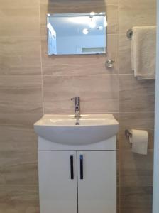 een badkamer met een witte wastafel en een spiegel bij Repton Private Hotel in Romford