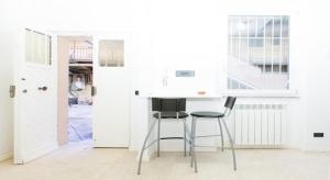 a white kitchen with a stool and a table at Parioli House near Borghese-LUISS University in Rome