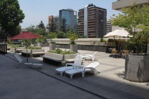 un patio con sedie bianche, tavoli e ombrelloni di La Gloria 30. Las Condes a Santiago