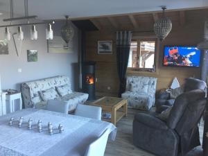 ein Wohnzimmer mit Tisch und Stühlen und einem Fernseher in der Unterkunft Le Rocher Blanc A in Courchevel
