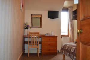 a room with a bed, chair and a tv at The Quaich B&B in Inverness