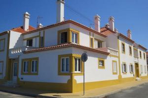 un gran edificio blanco y amarillo en una calle en Casas do Zé Zambujeira do Mar, en Zambujeira do Mar