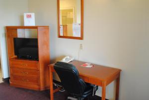 Habitación con escritorio, TV y silla. en Economy Inn, en Edmonton