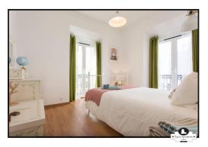 um quarto com uma grande cama branca e janelas em Canto do 28, Typical Apartment em Lisboa