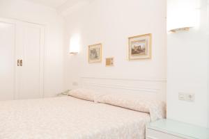 1 dormitorio blanco con 1 cama y 2 cuadros en la pared en Rey Fernando en Santiago de Compostela