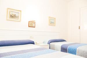 2 camas en una habitación con paredes blancas en Rey Fernando, en Santiago de Compostela
