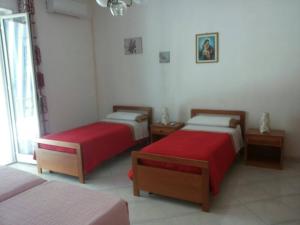 ポッツァッロにあるCasa Tre Roseの赤いシーツが備わるベッド2台付きの部屋