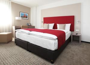 a bedroom with a large bed with a red headboard at Golden Tulip Kassel Hotel Reiss in Kassel