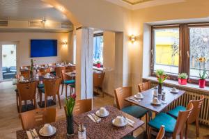 ein Restaurant mit Tischen und Stühlen und einem großen Fenster in der Unterkunft Ahorn Hotel in München